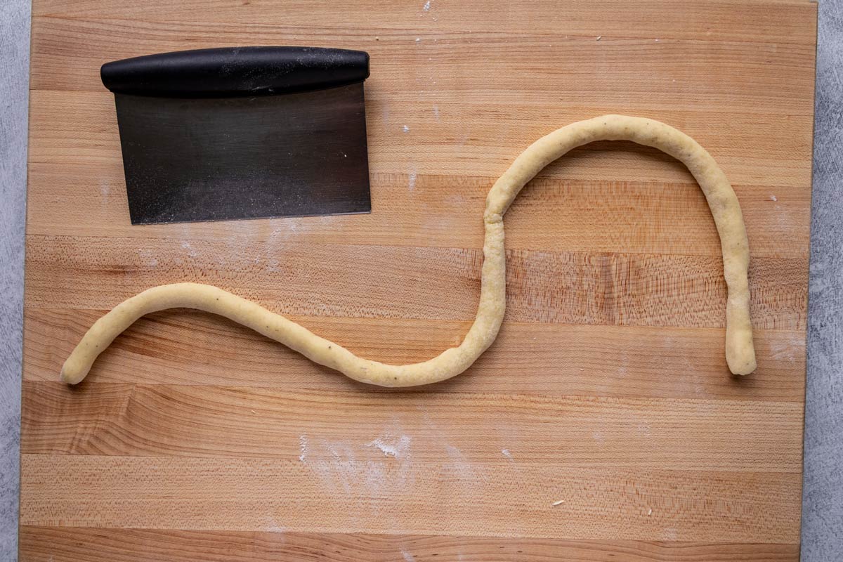 A long rope of dough arranged like a wave on a wooden board.