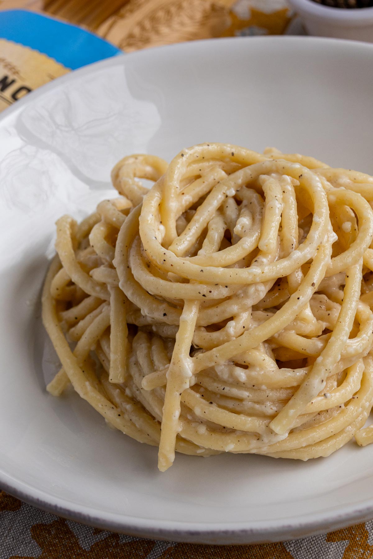 Bucatini cacio e pepe twirled into a mound in a pasta bowl.