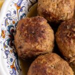Four giant Dutch gehaktballen meatballs in an oval dish.