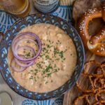 Obatzda beer cheese dip in a blue bowl surrounded by hard and soft pretzels.