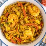 A bowl of Singapore noodles with plump shrimp and colorful strips of vegetables.