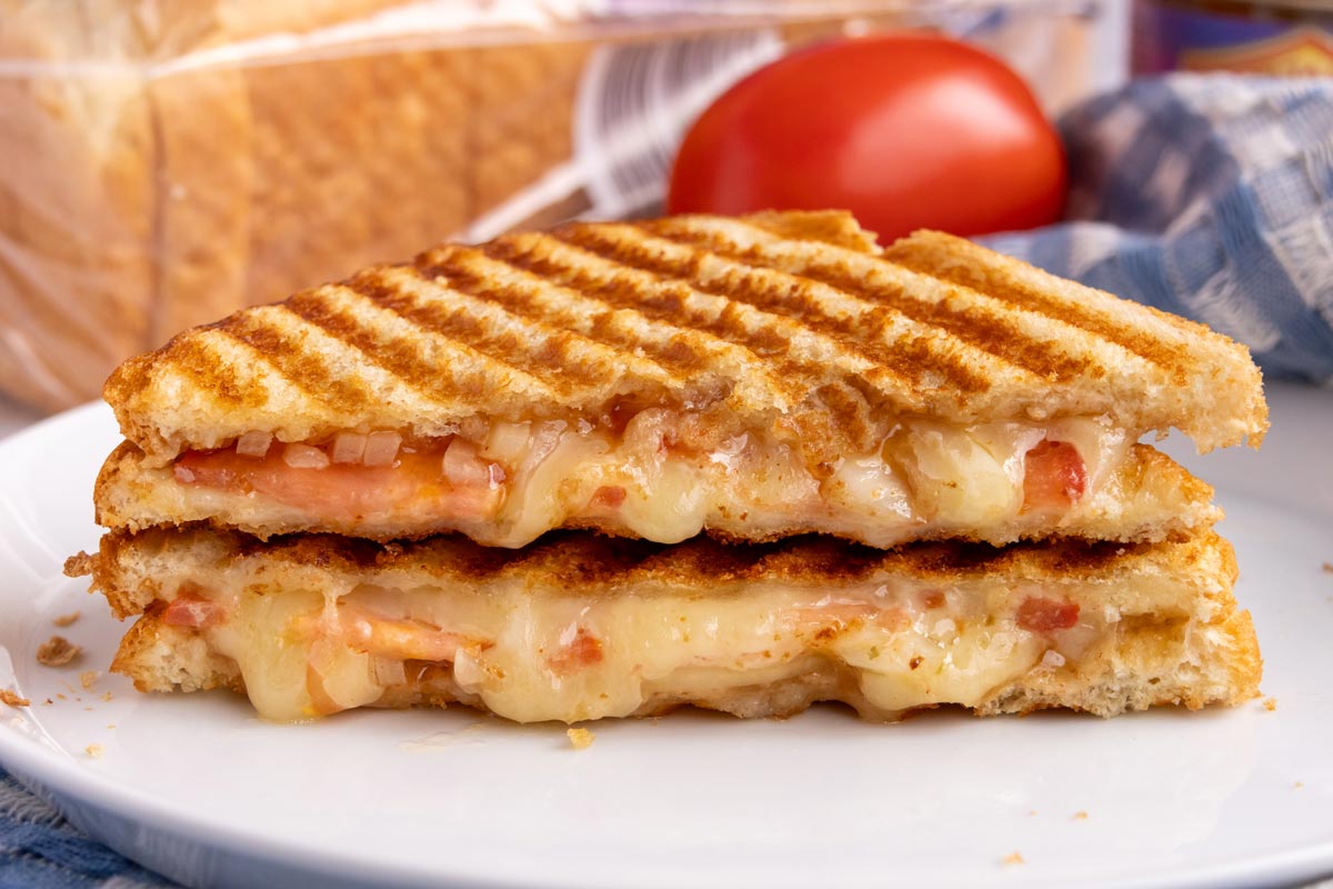Two halves of a Braaibroodjie sandwich stacked on top of each other showing of the filling.