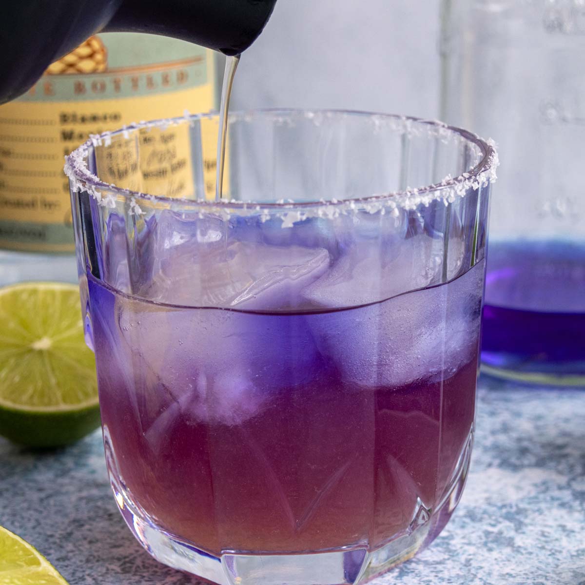 Pouring a cocktail shaker of liquid into a glass of blue tequila as most of it has turned purple.