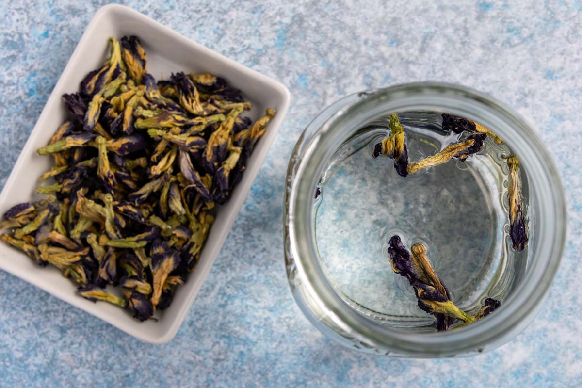 Dry butterfly pea flowers added to a jar of silver tequila.
