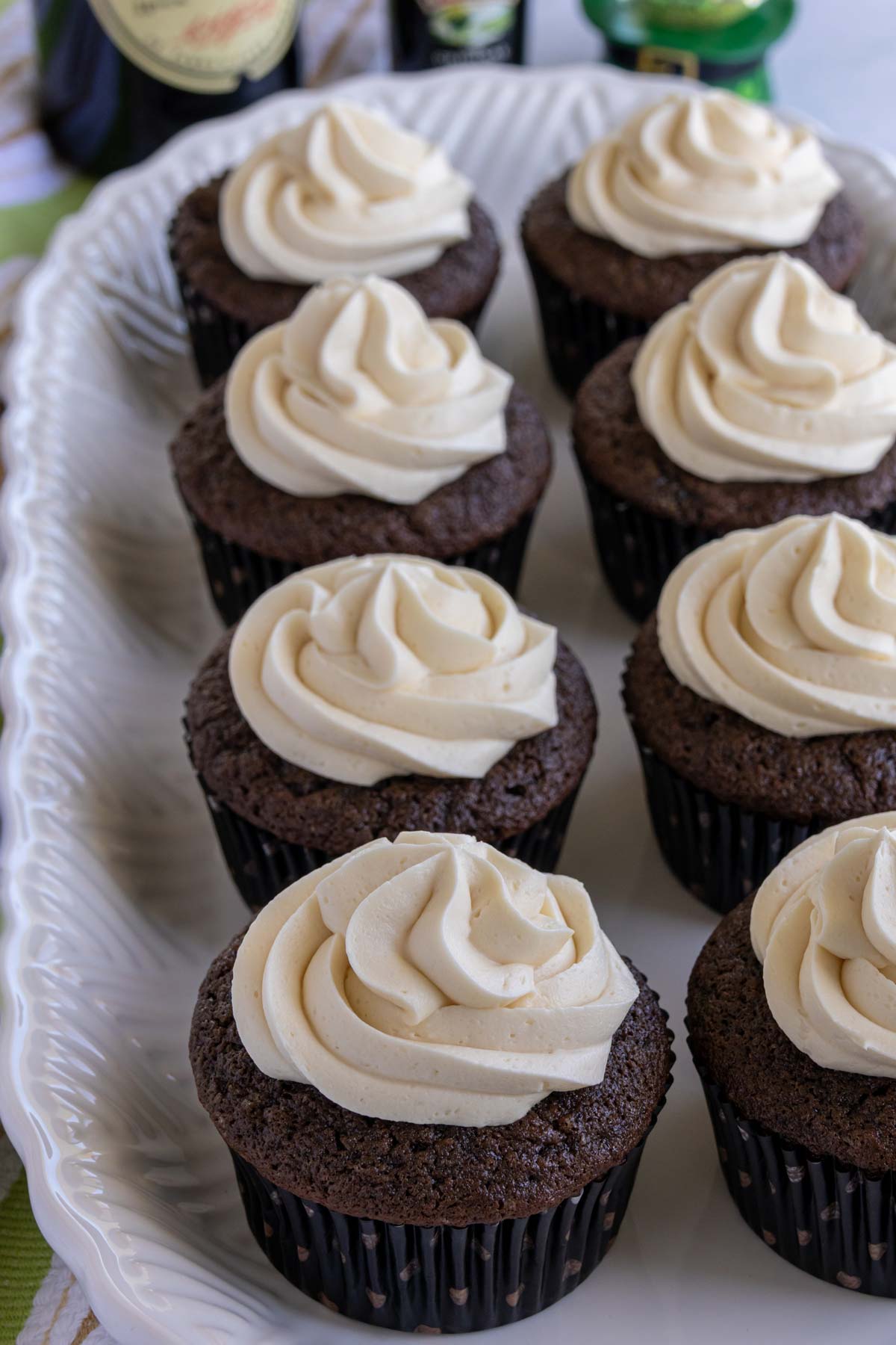 Chocolate Guinness cupcakes with Bailey's frosting with black and white polka dot wrappers on a white platter.