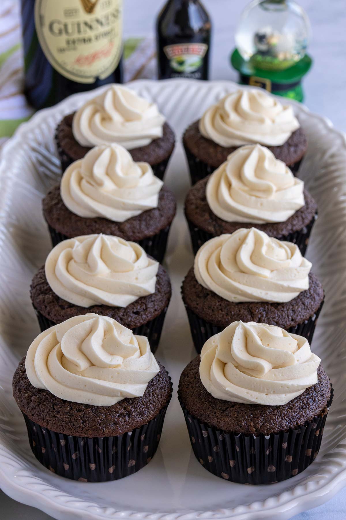 Eight chocolate Guinness cupcakes with Bailey's frosting on a white platter.