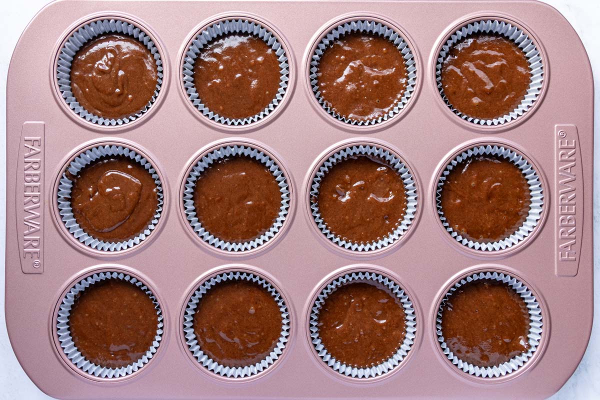 Chocolate Guinness cupcake batter divided between cups in a muffin pan.