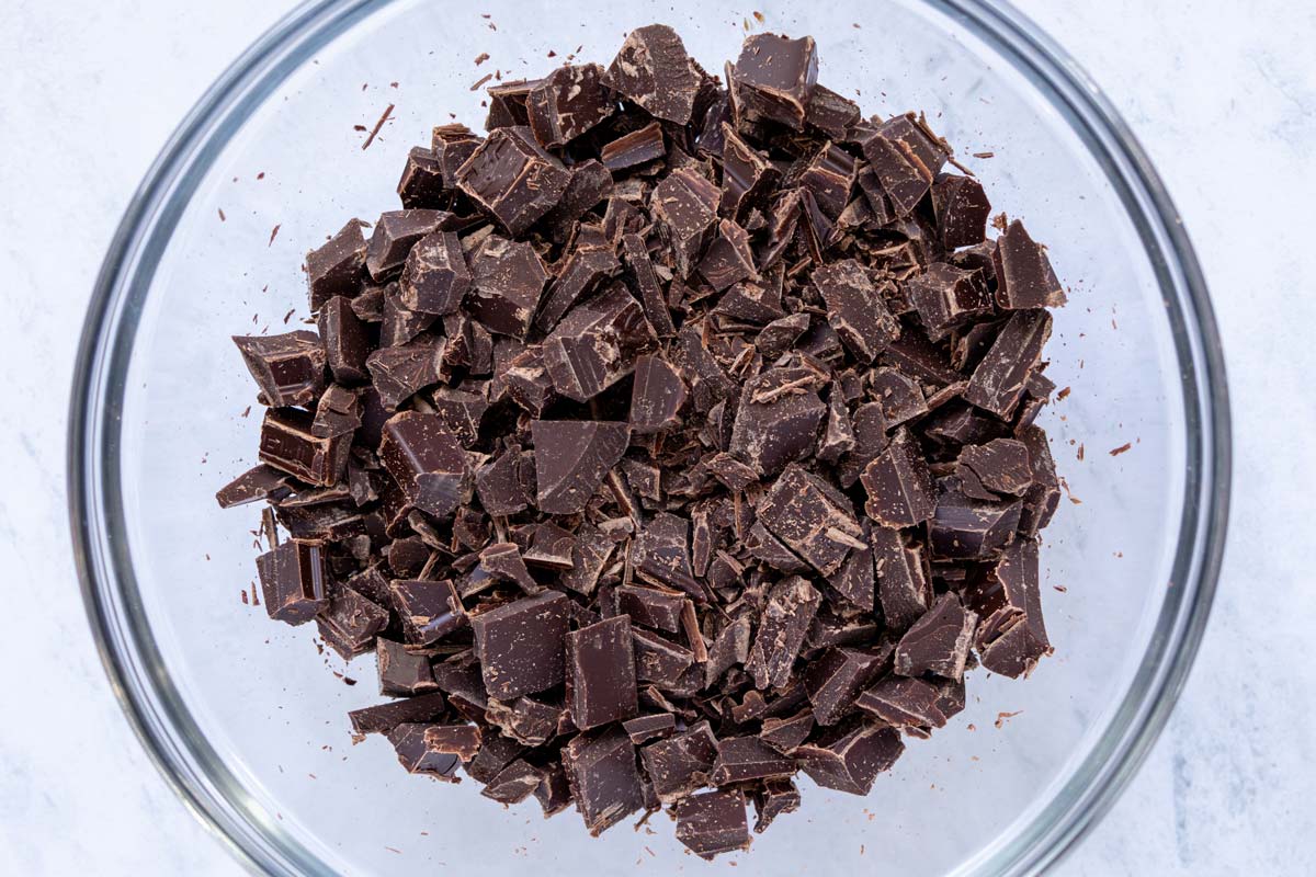 Chopped bittersweet chocolate in a small glass bowl.