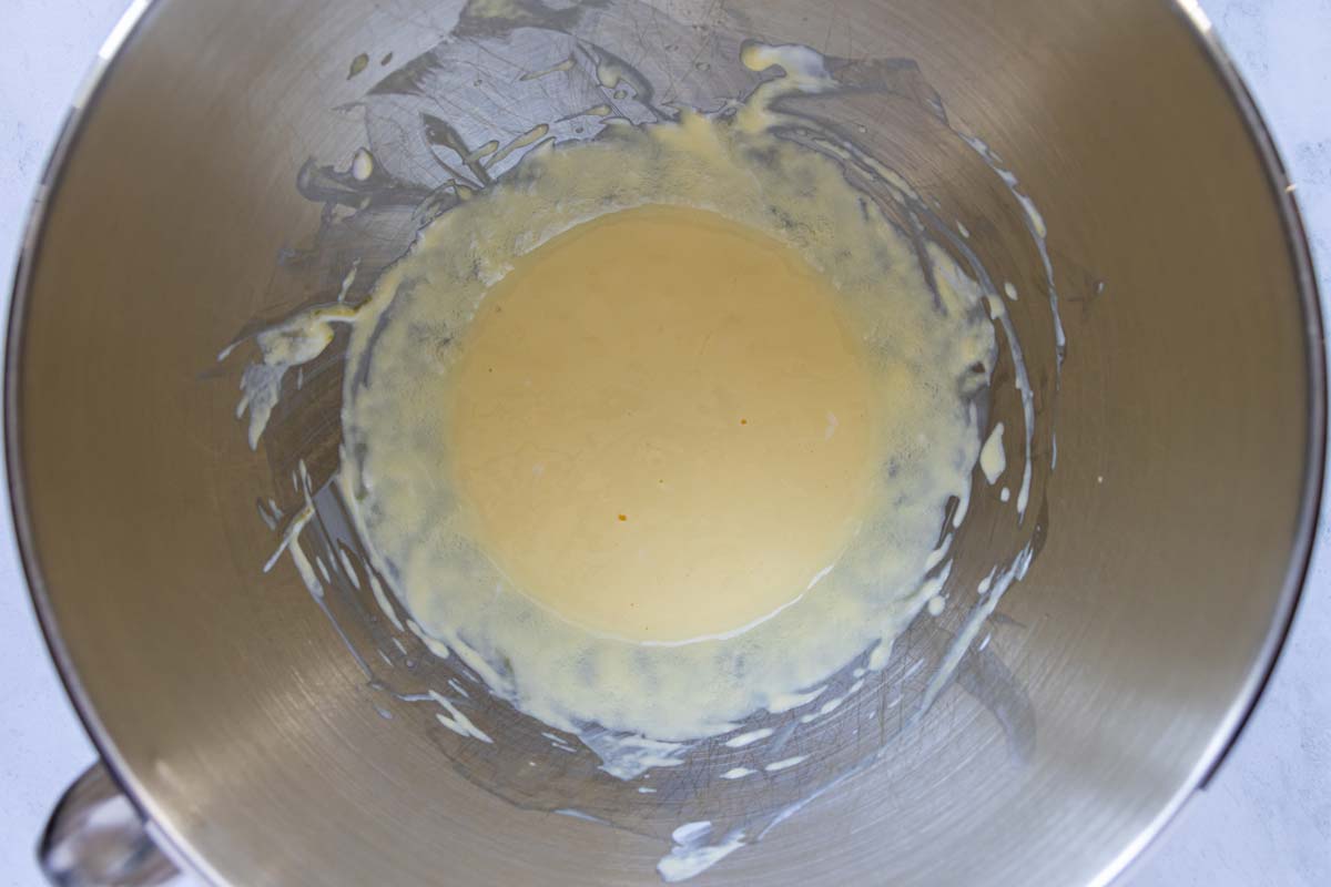 Sour cream and an egg beaten together in a metal mixing bowl.