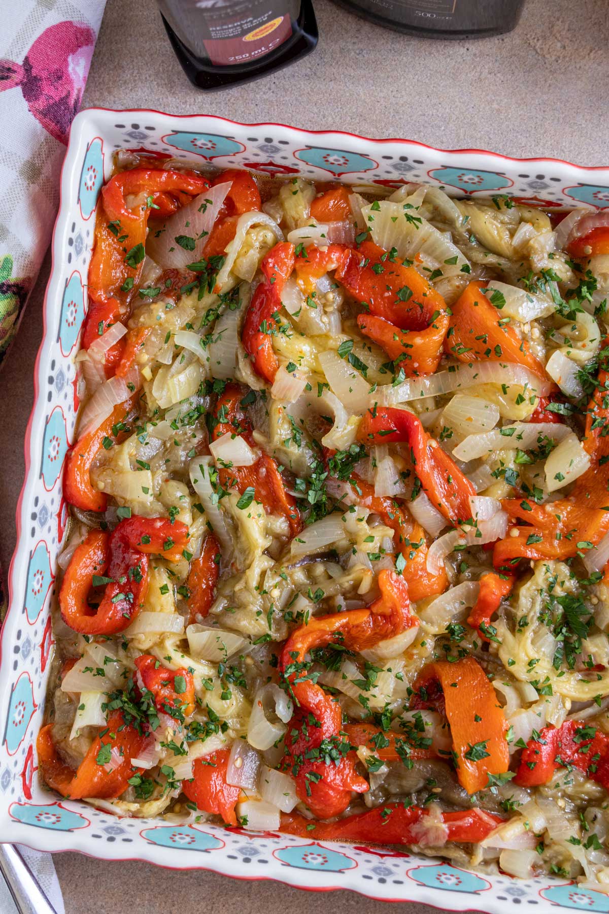 Catalan roasted vegetables (escalivada) served in a square dish, topped with chopped parsley.
