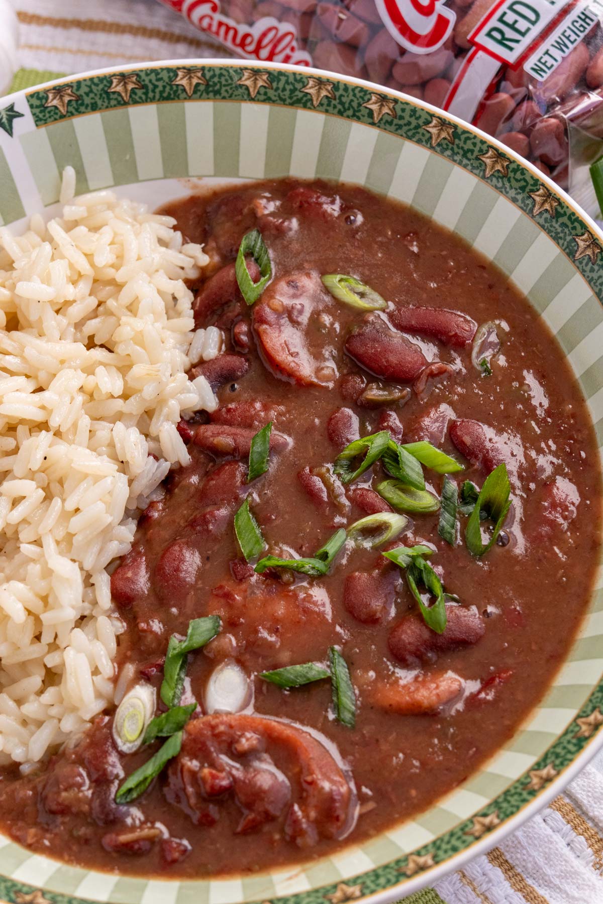 Red beans and rice with andouille sausage garnished with sliced scallions in a wide bowl.
