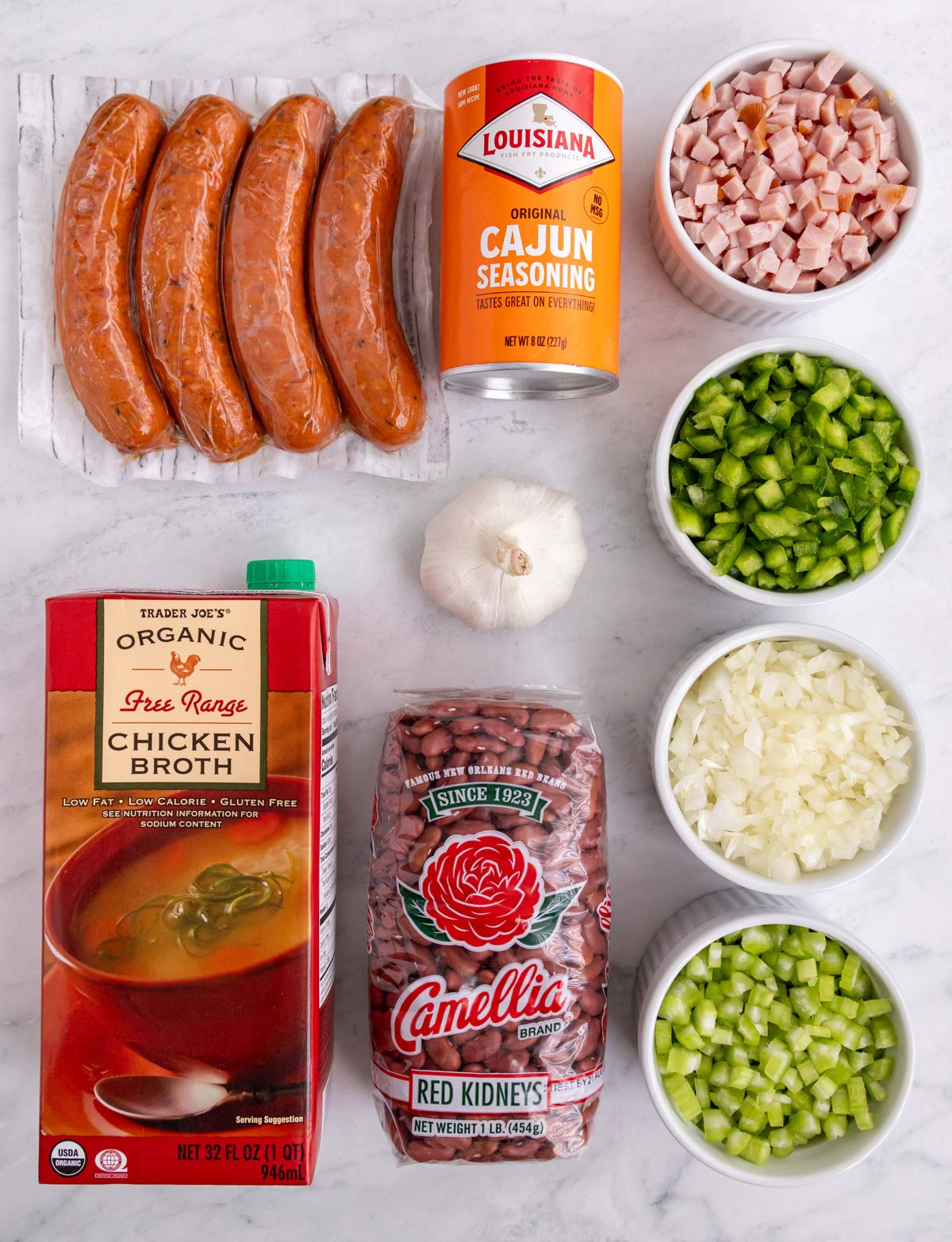 Ingredients for red beans and rice on a white marble background.