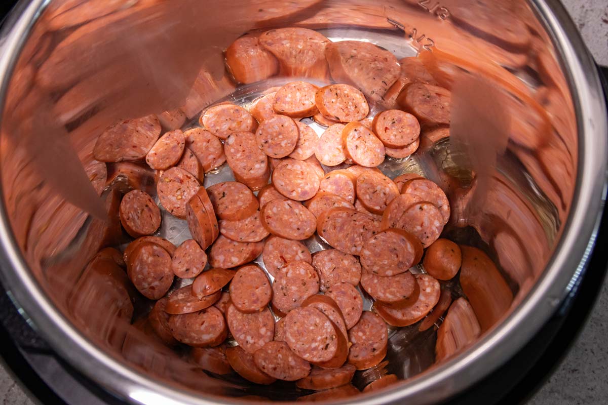 Sliced andouille sausage cooking in an Instant Pot.