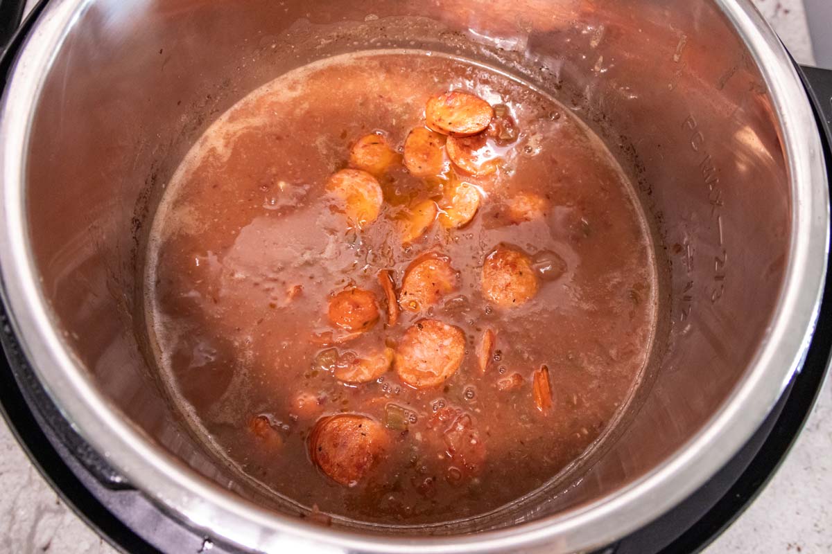 Sliced seared andouille sausage added to a mixture of cooked slightly pureed beans.