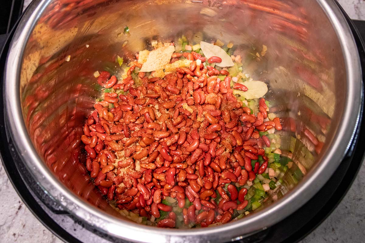 Red kidney beans added to a mixture in an Instant Pot.