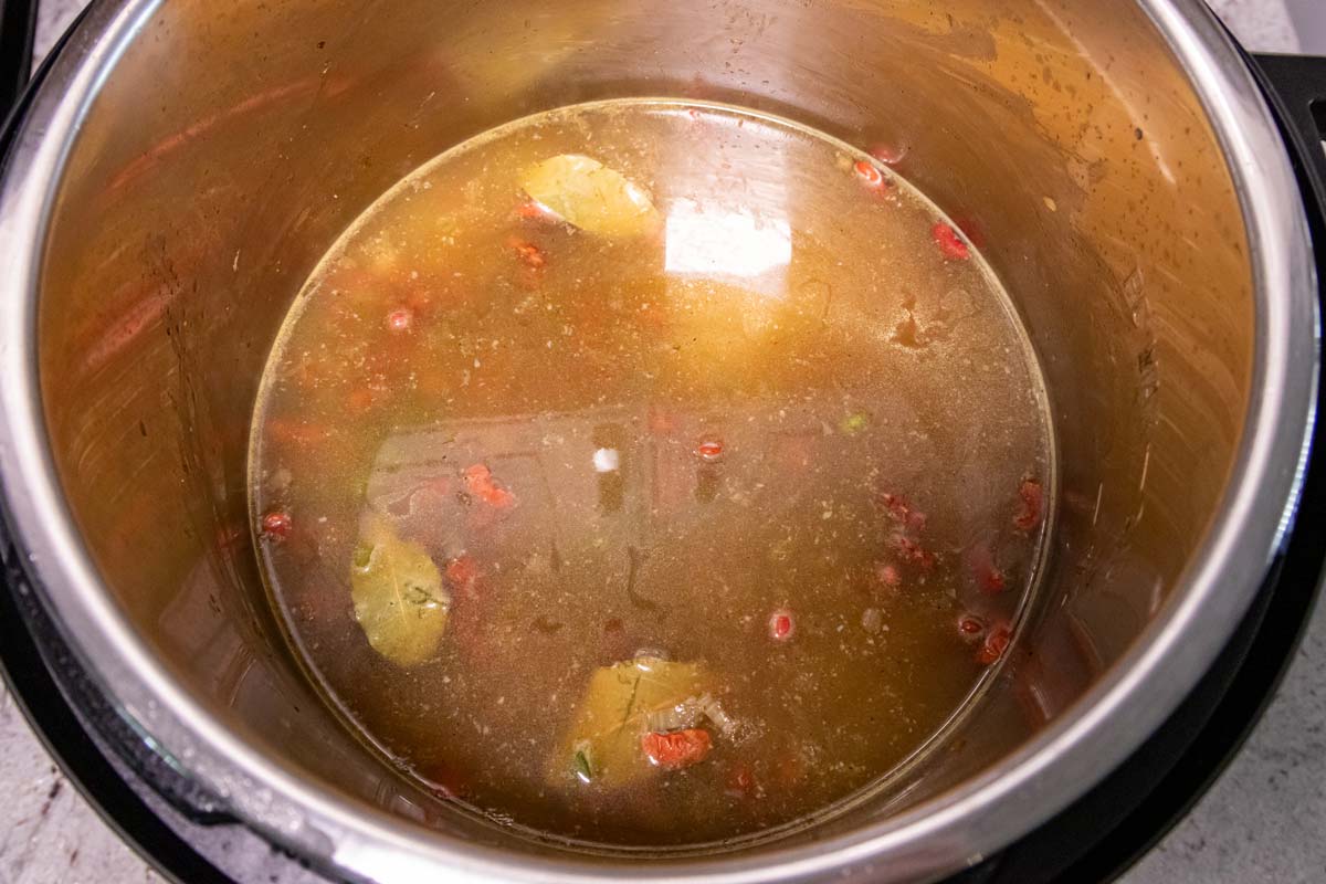 An Instant Pot after adding broth and water to the mixture inside.