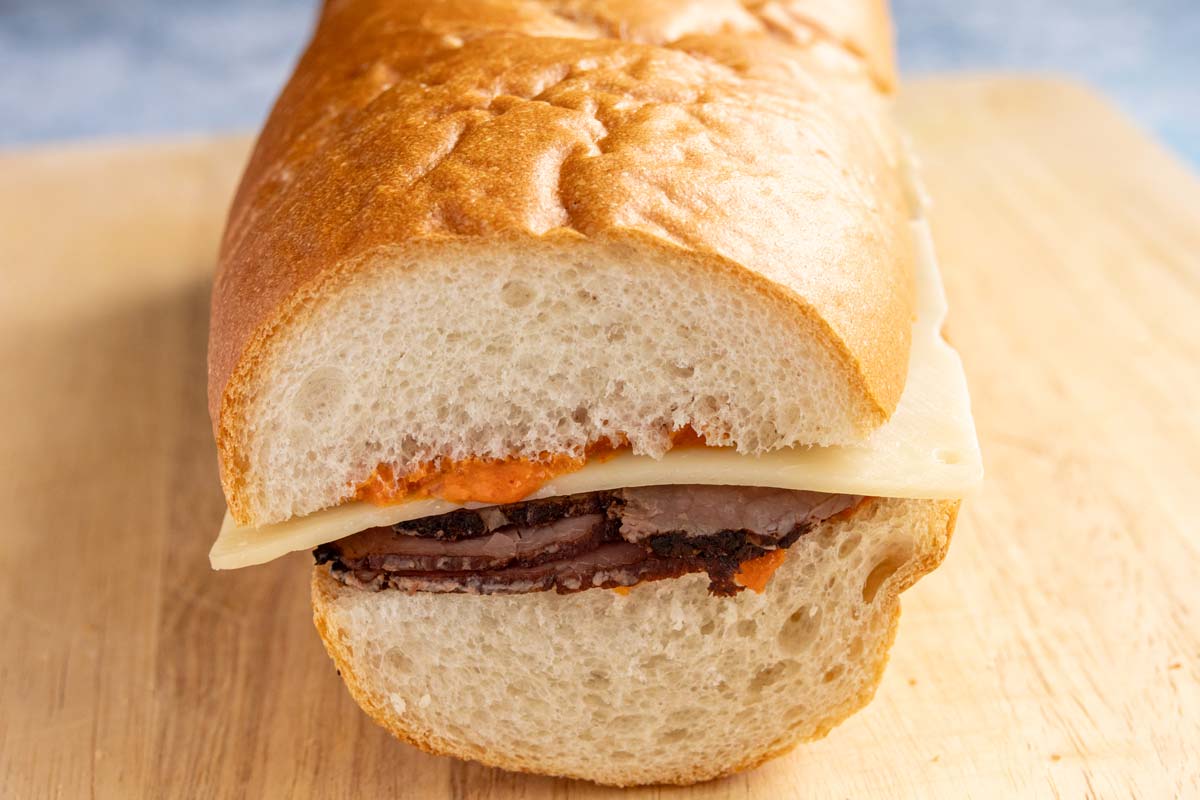 An assembled pan con bistec sandwich before cooking in a sandwich press.