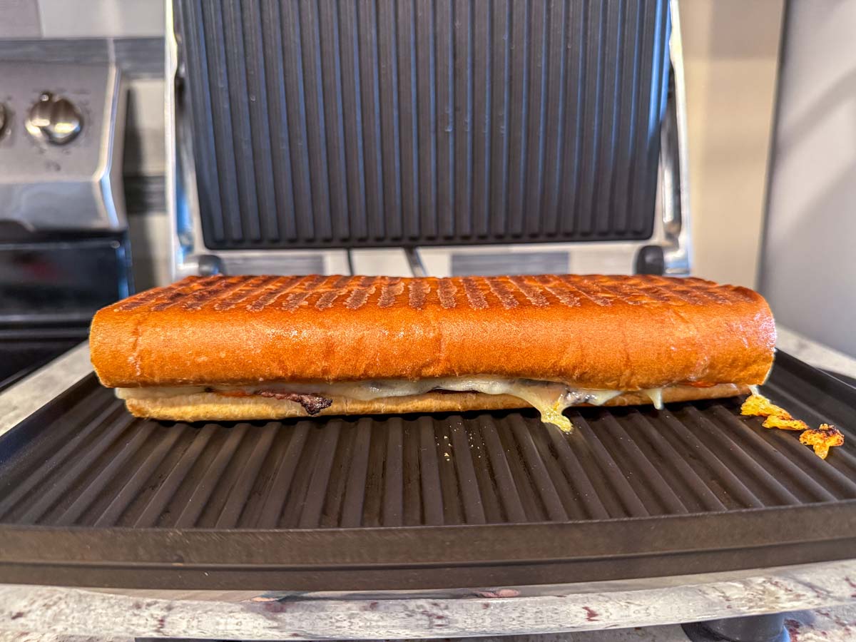 A Cuban steak sandwich with crispy bread pressed in a panini maker creating grill marks.