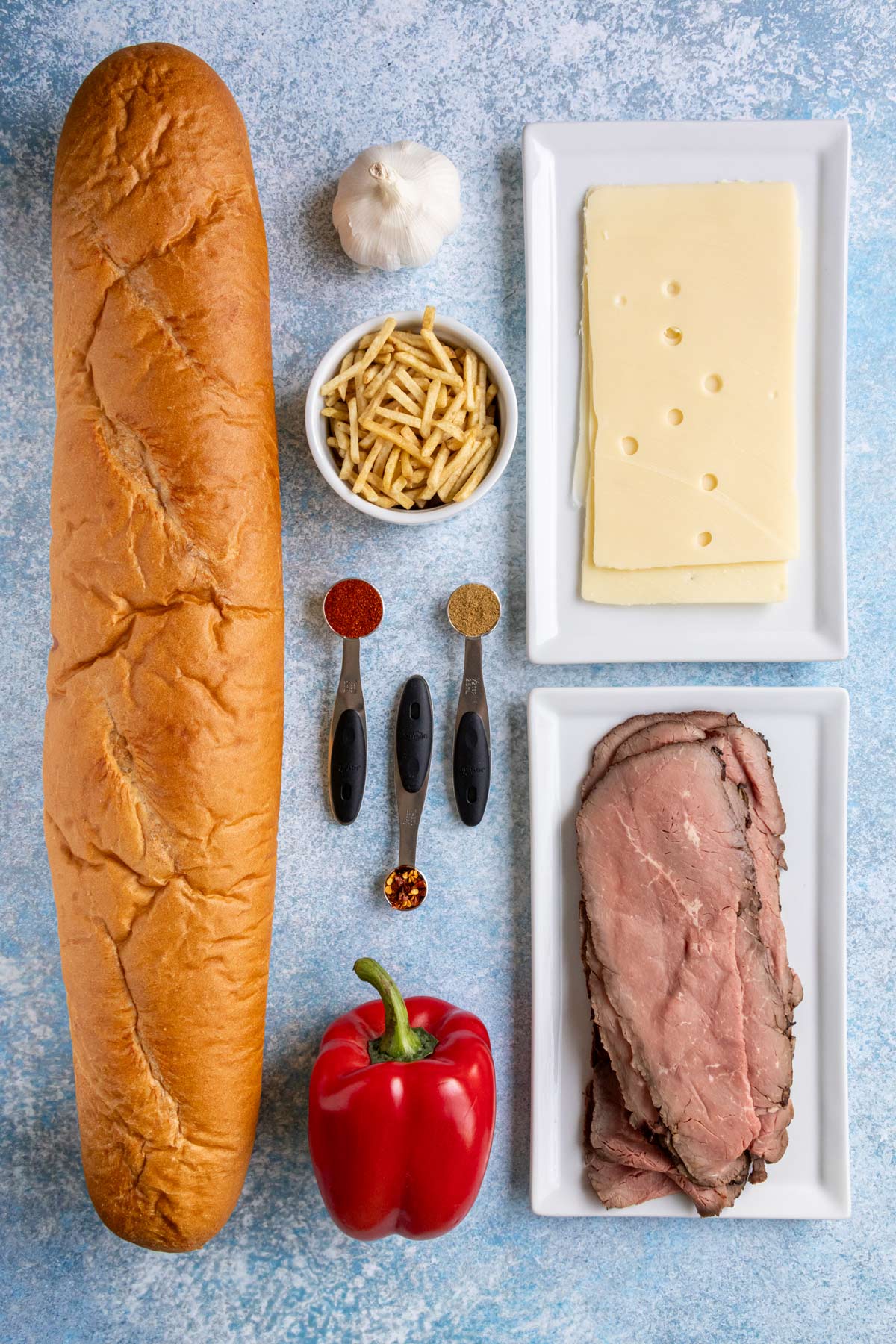 Ingredients for pan con bistec on a blue and white speckled background.