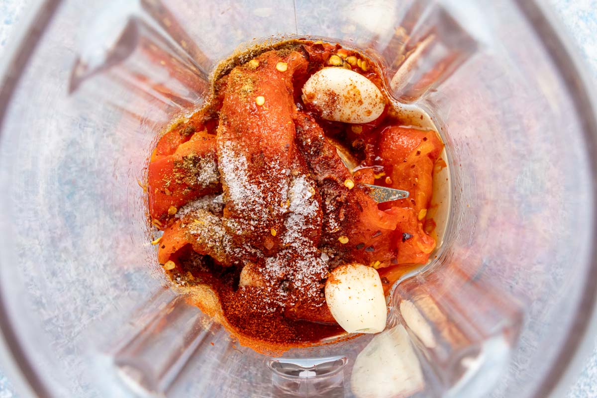 Roasted red pepper, garlic cloves, vinegar, ground cumin, salt, and chili flakes added to a blender.