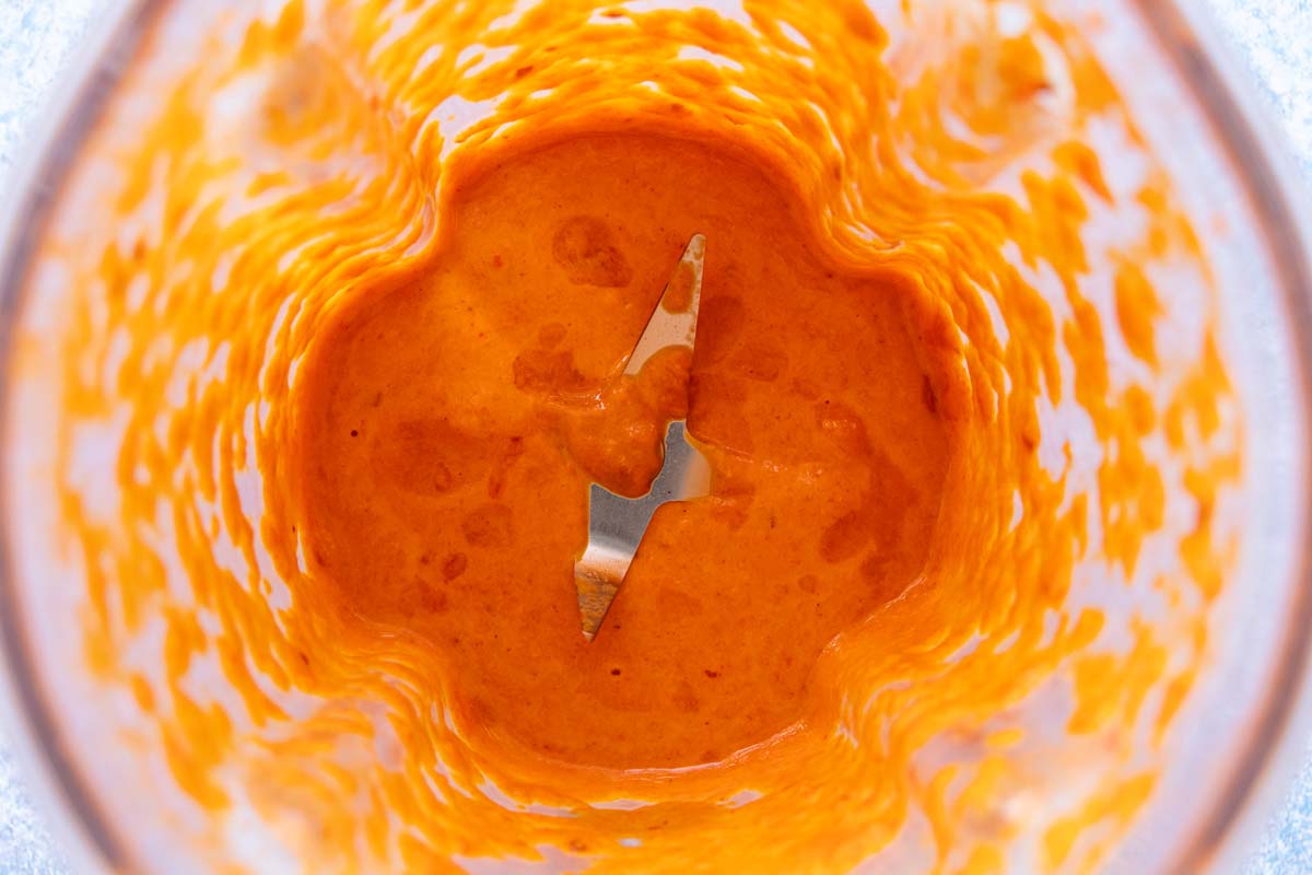 A creamy orange mixture in the jar of a blender.