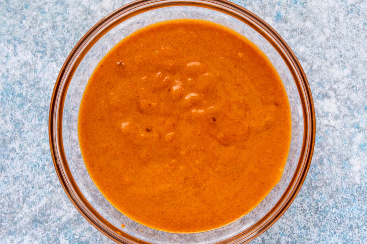 A bright orange mojo rojo sauce in a small glass bowl.