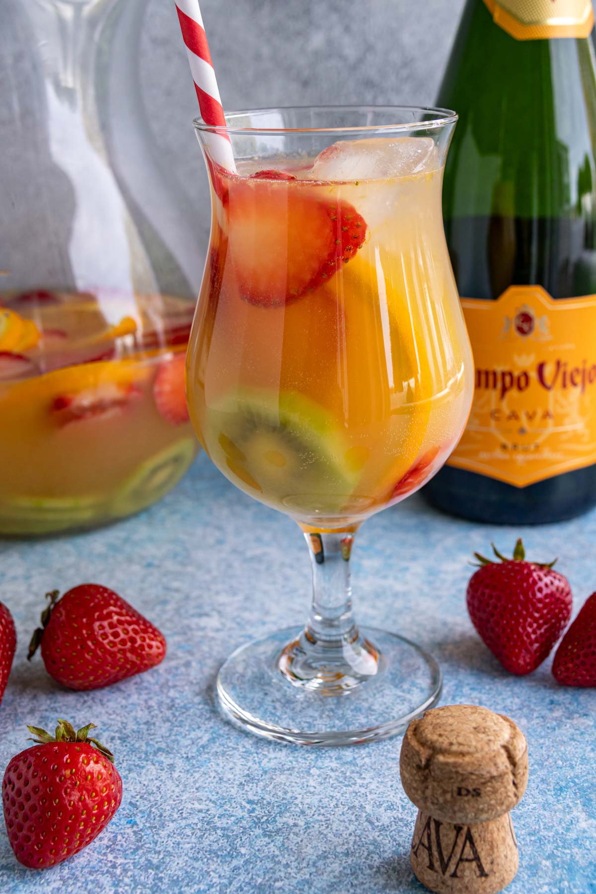 Cava sangria served in a hurricane-style glass with striped red and white straw.
