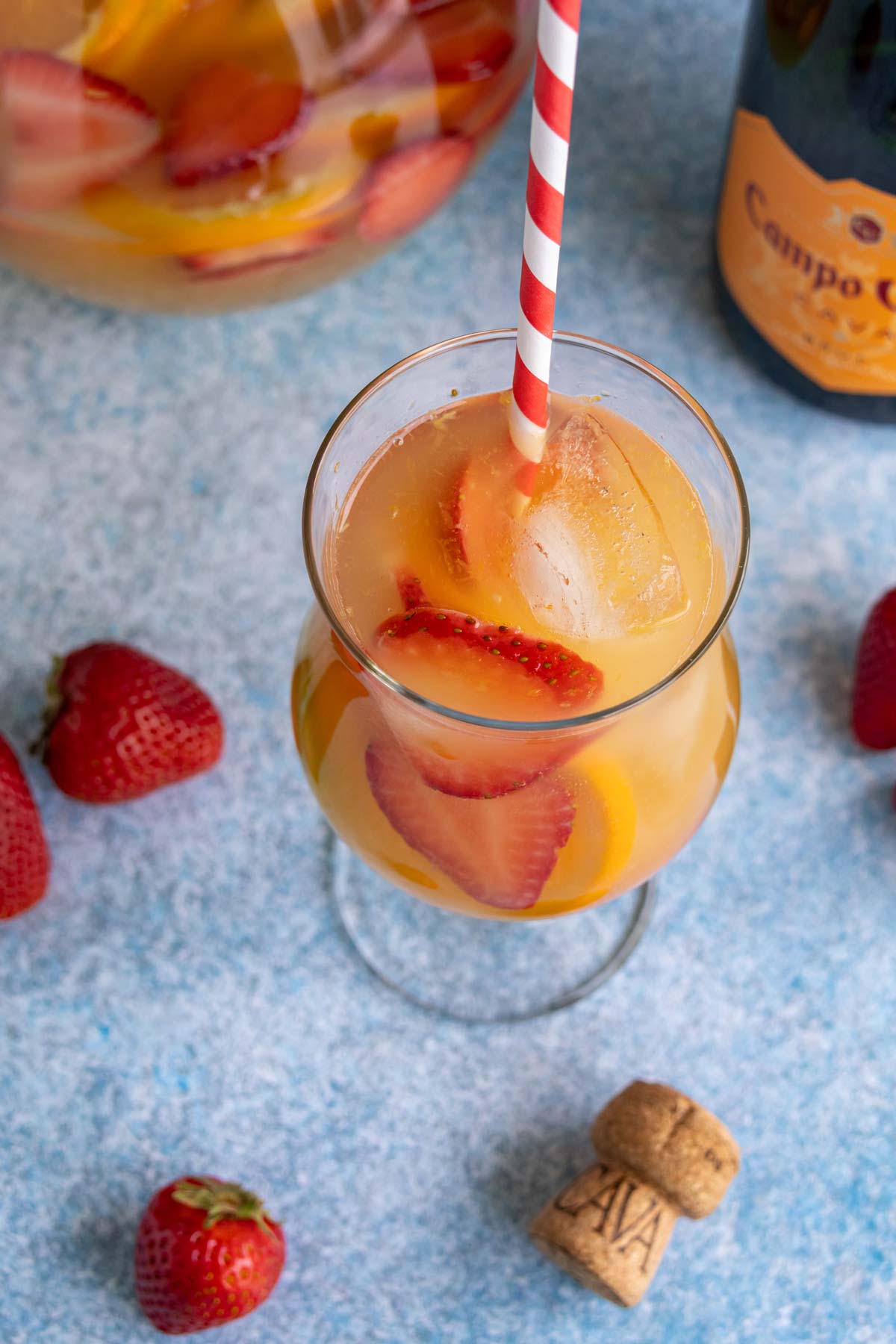 A glass of cava sangria with a red and white striped straw.