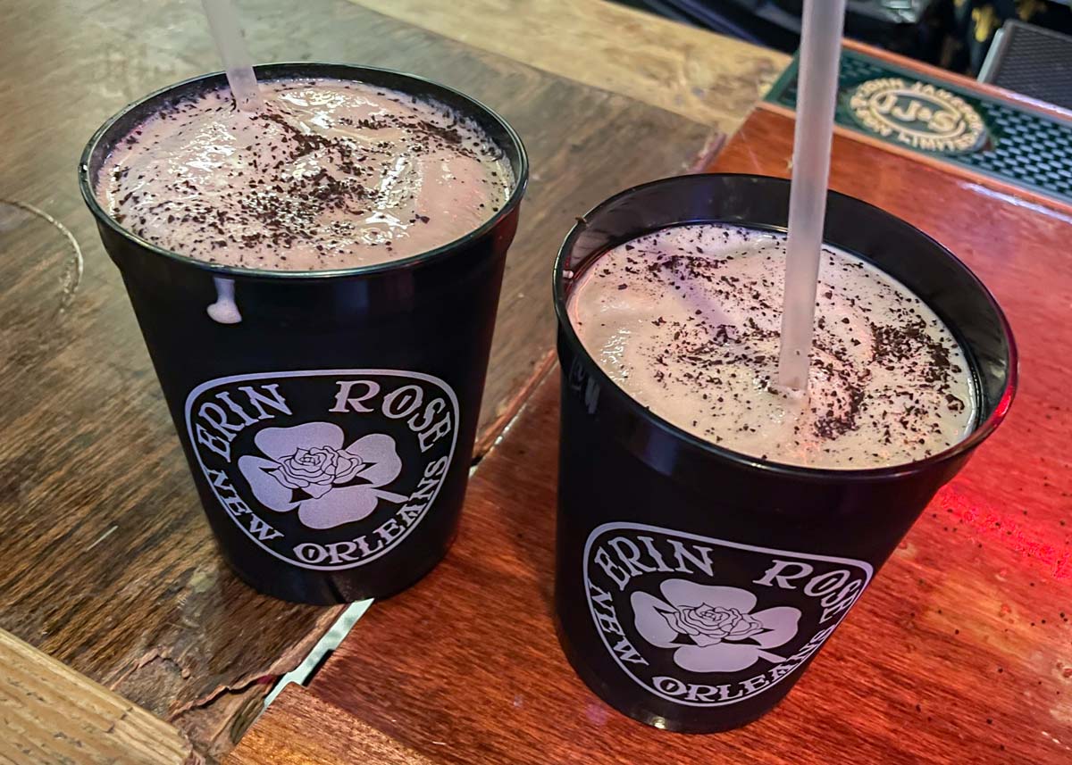 Two black plastic cups that say Erin Rose New Orleans filled with frozen Irish coffee.