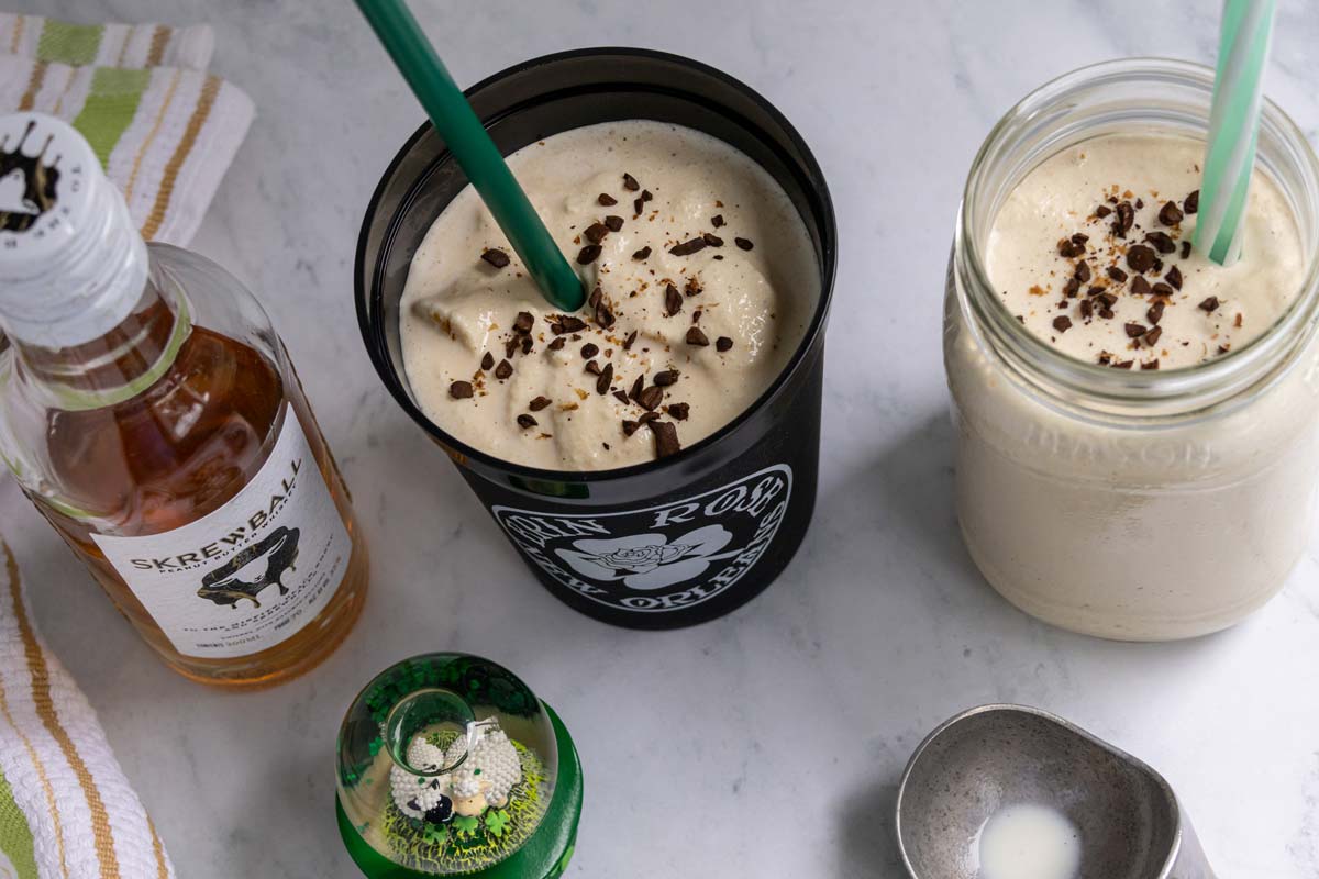 Two cups of frozen Irish coffee garnished with coffee grounds and served with green straws.