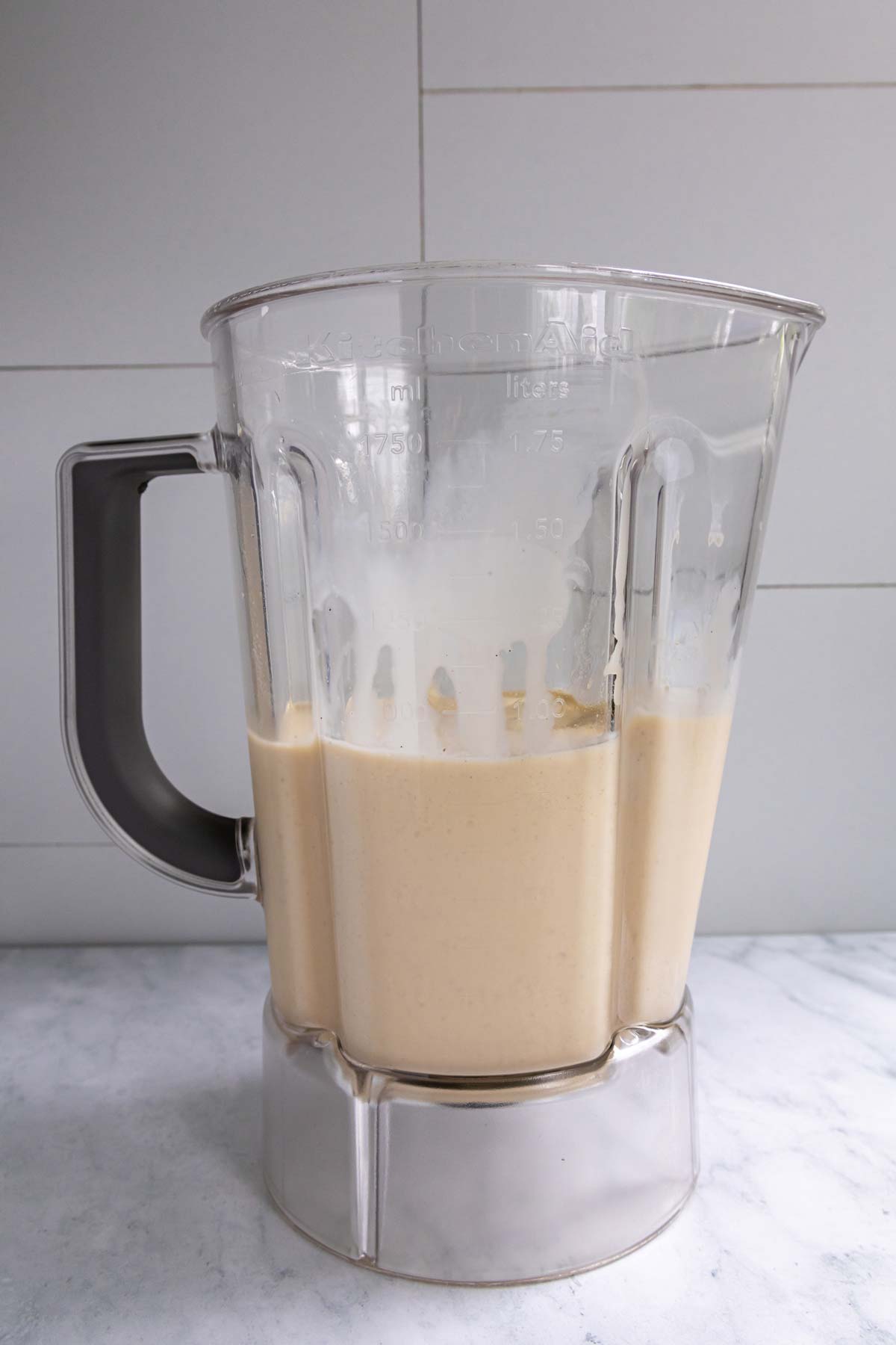 Coffee ice cubes, vanilla ice cream, and peanut butter whiskey in a blender jar after blending.