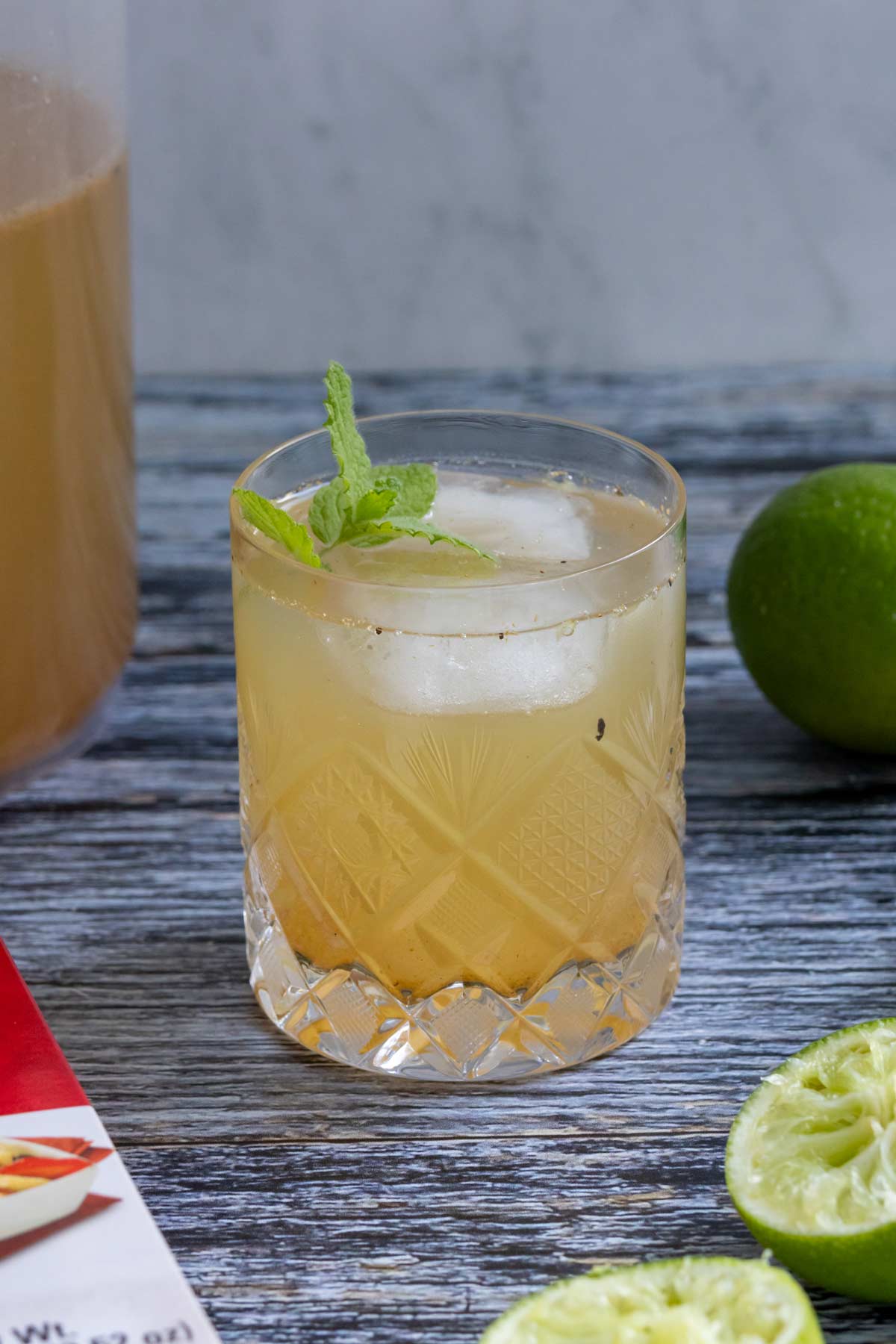 Shikanji Indian lemonade in a crystal glass with a sprig of mint garnish on a grey wooden surface.