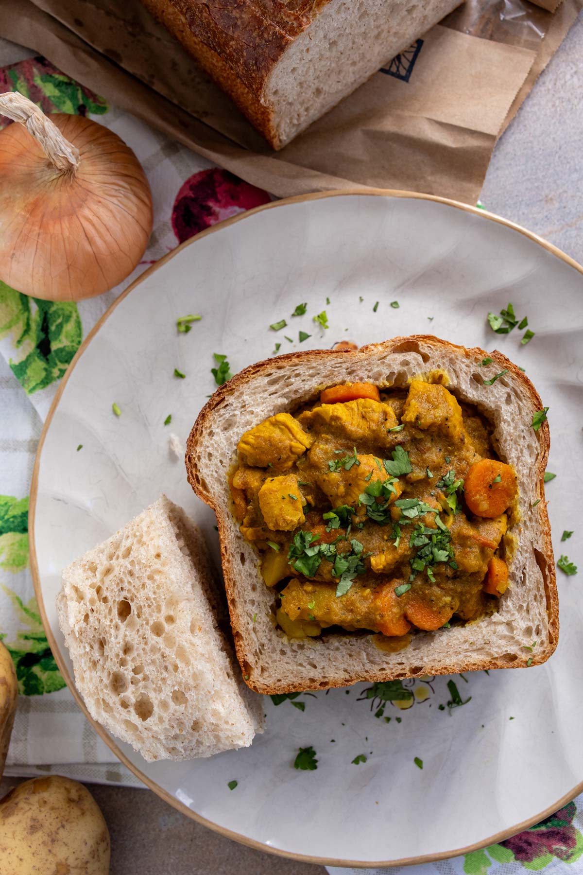 Chicken bunny chow with the hollowed out portion of bread served alongside it.