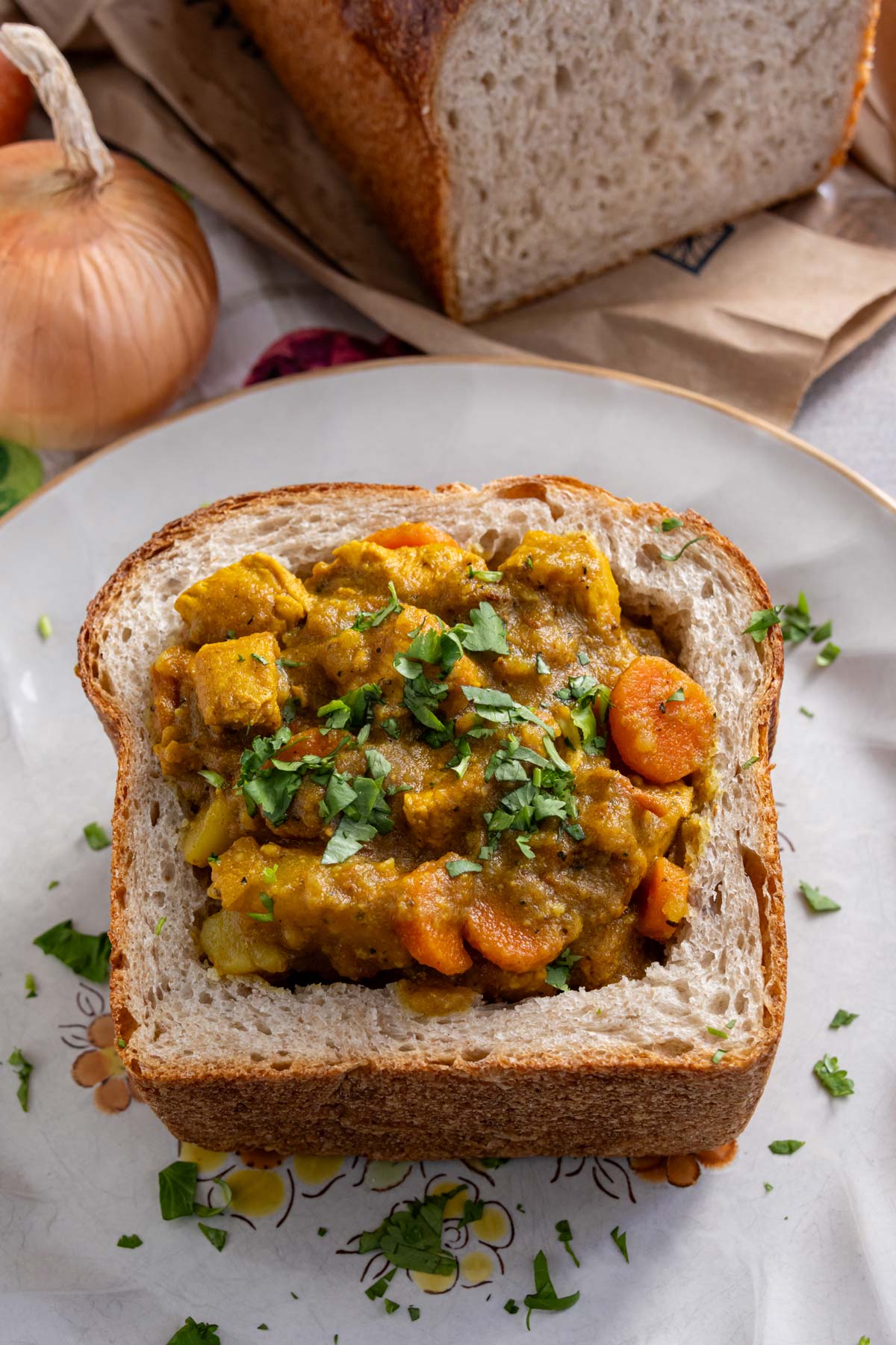 South African chicken curry with potatoes and carrots, served in a bread bowl.