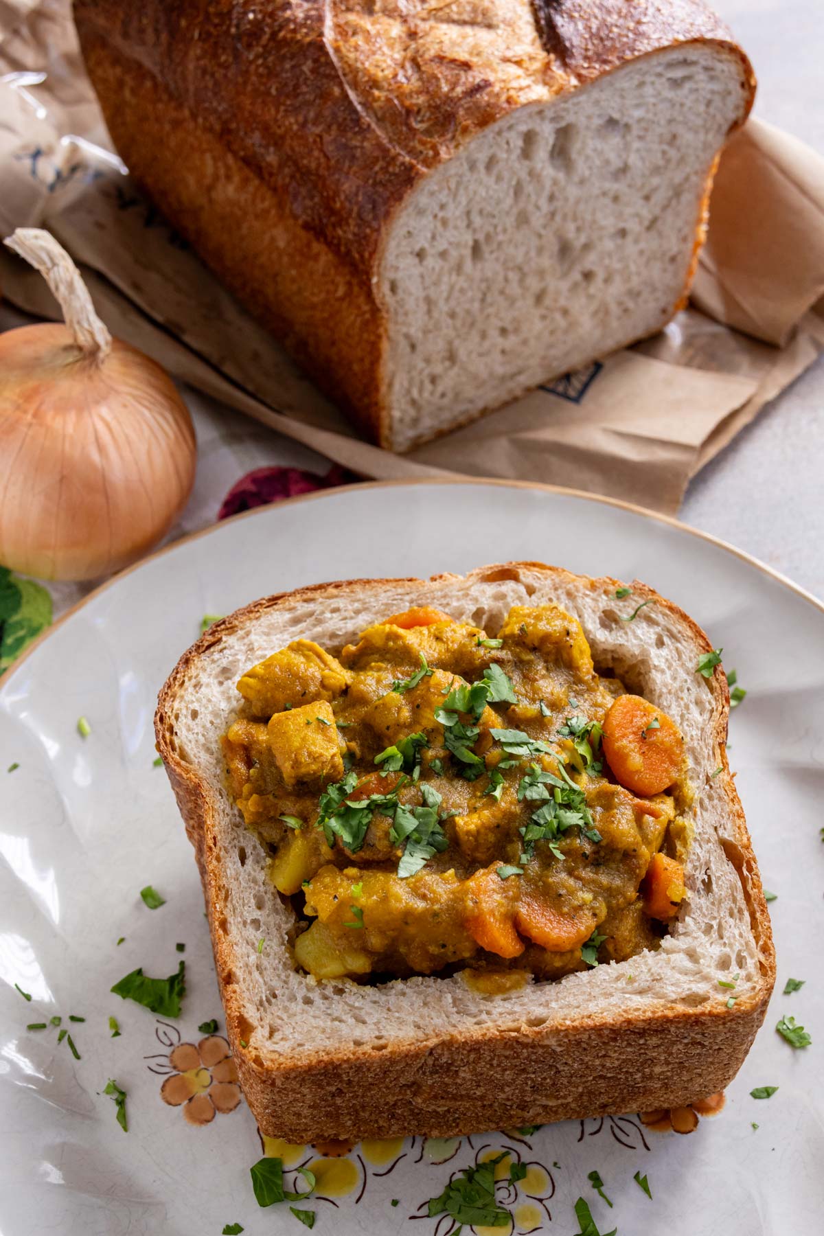 Bunny chow with chicken, carrots, and potatoes, served in a quarter loaf of sourdough bread.