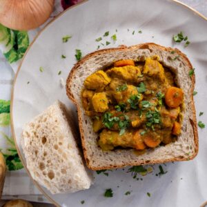Chicken bunny chow with the hollowed out portion of bread served alongside it.