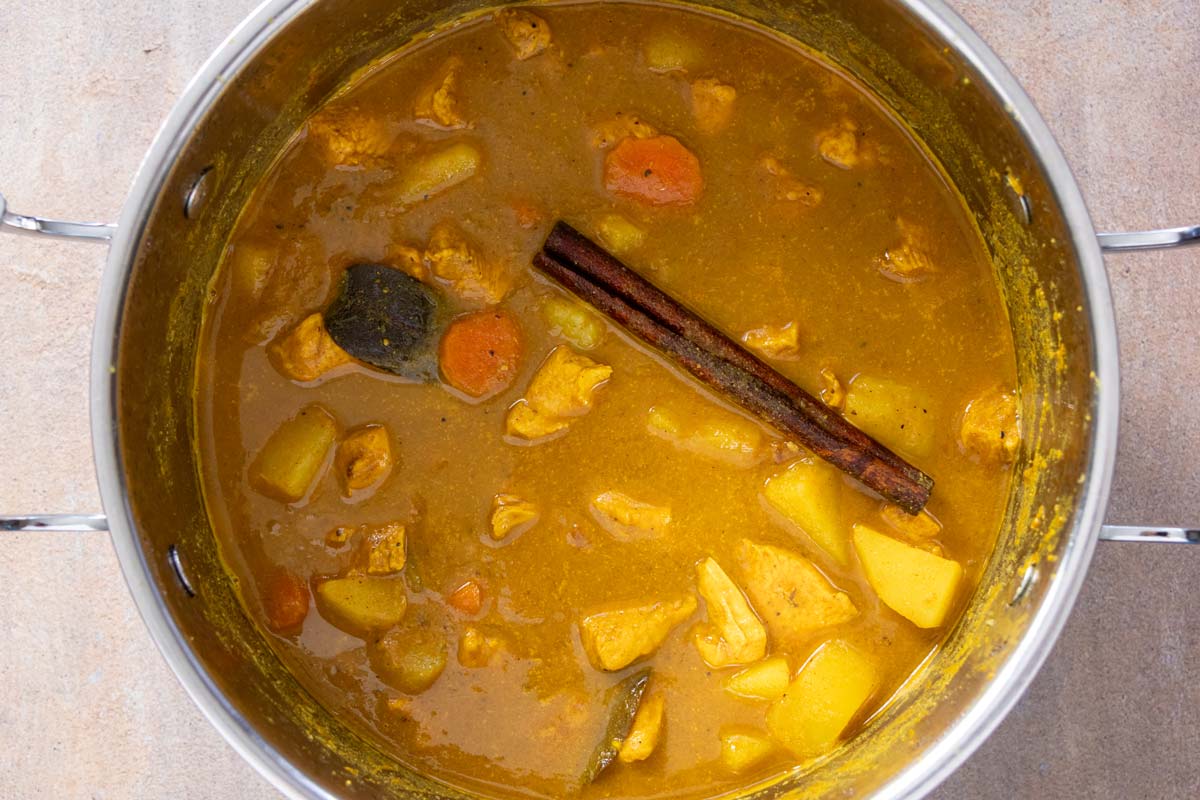 Duban-style chicken and potato curry cooked in a metal pot.