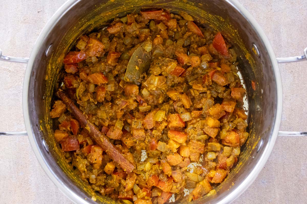 A mixture of diced vegetables and curry cooking in a metal pot.