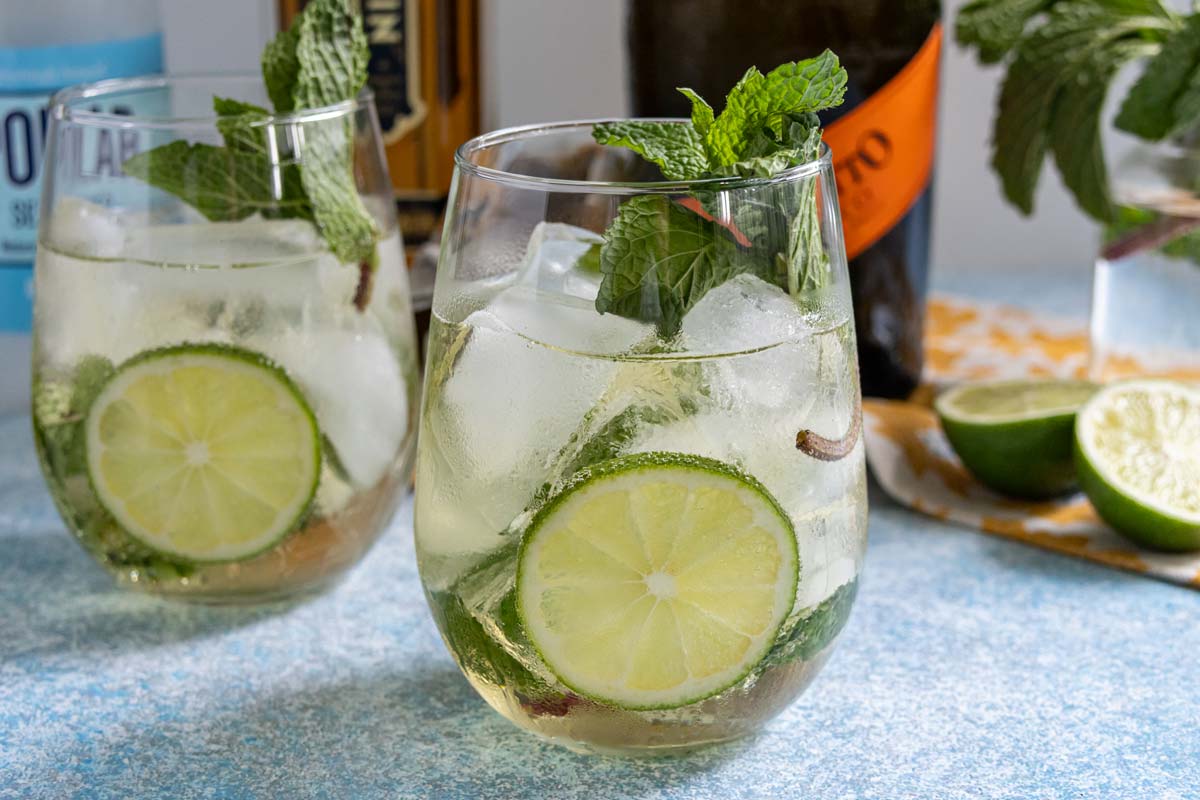 Hugo Spritz cocktails served in stemless wine glasses with slices of lime and fresh mint garnishes.