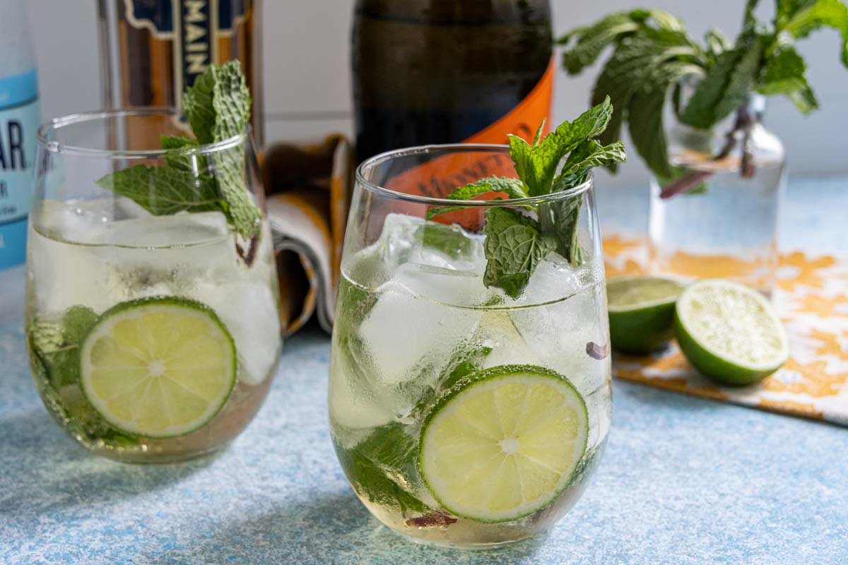 Hugo Spritz cocktails served in stemless wine glasses with slices of lime and fresh mint garnishes.