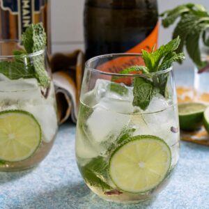 A Hugo Spritz cocktail garnished with a lime slice and sprig of fresh mint.