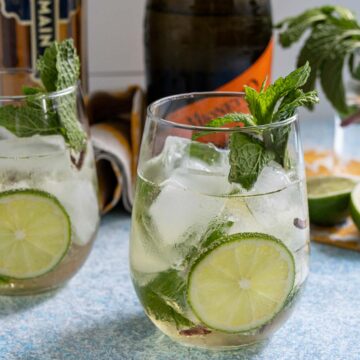 A Hugo Spritz cocktail garnished with a lime slice and sprig of fresh mint.
