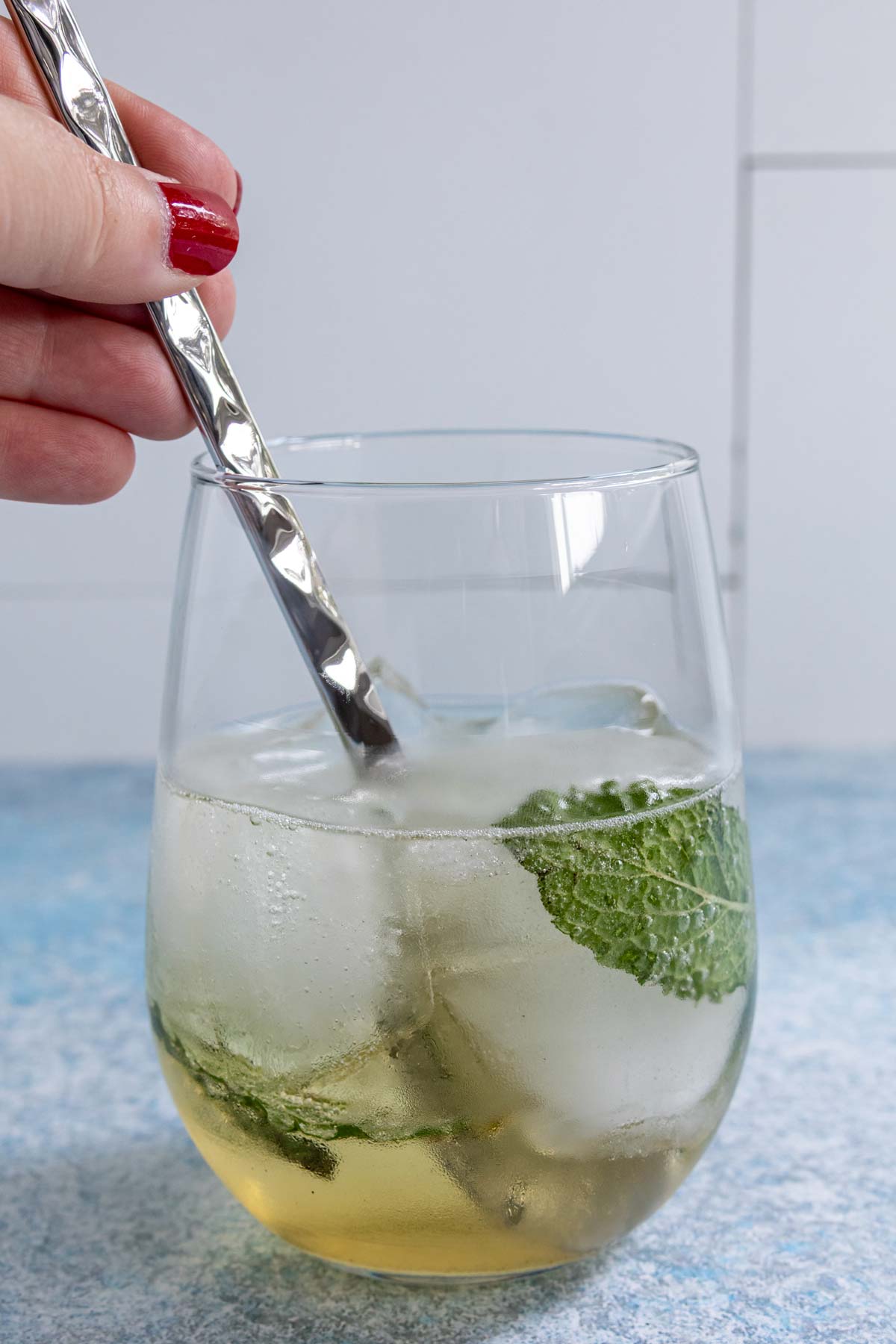 Stirring a Hugo Spritz cocktail with a bar spoon.