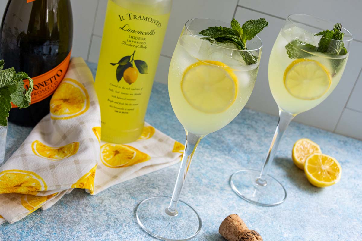 Two glasses of Limoncello Spritz with bottles of Limoncello and prosecco next to them.