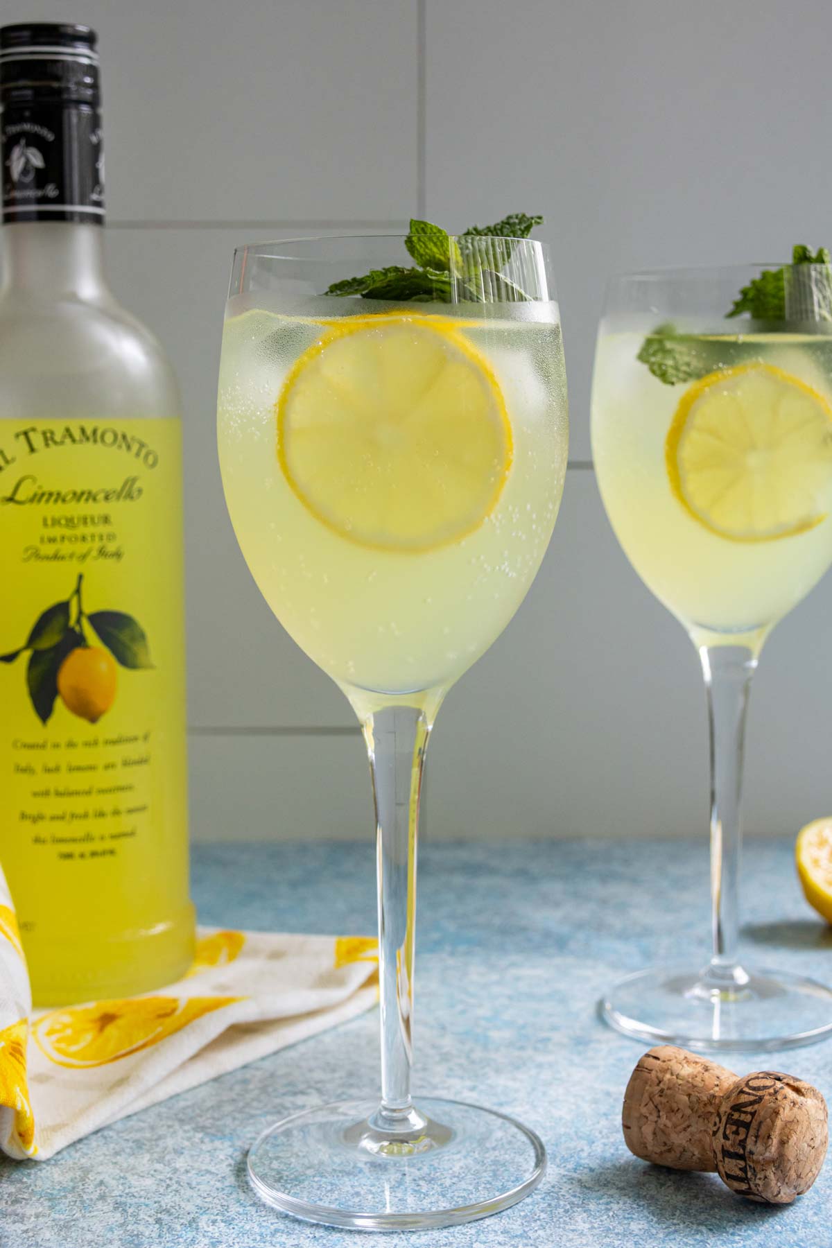 Limoncello Spritz in a wine glass garnished with a slice of lemon and sprig of mint.