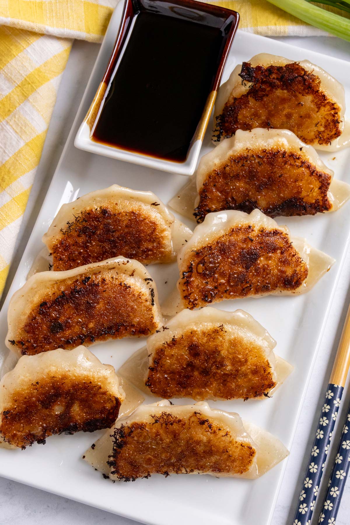 Pan-fried pork and shrimp dumplings arranged crispy side up on a white rectangular plate.