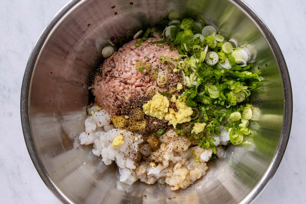 Pork and shrimp dumpling filling ingredients in a bowl before mixing together.