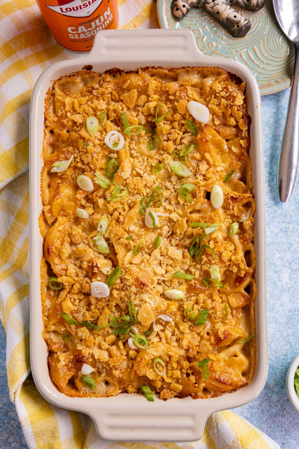 A rectangular casserole of Cajun macaroni and cheese topped with crushed Ritz crackers and sliced scallions.