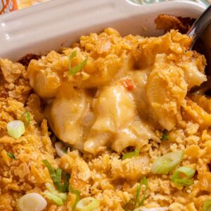 A spoon scooping baked Cajun macaroni and cheese out of a casserole dish.