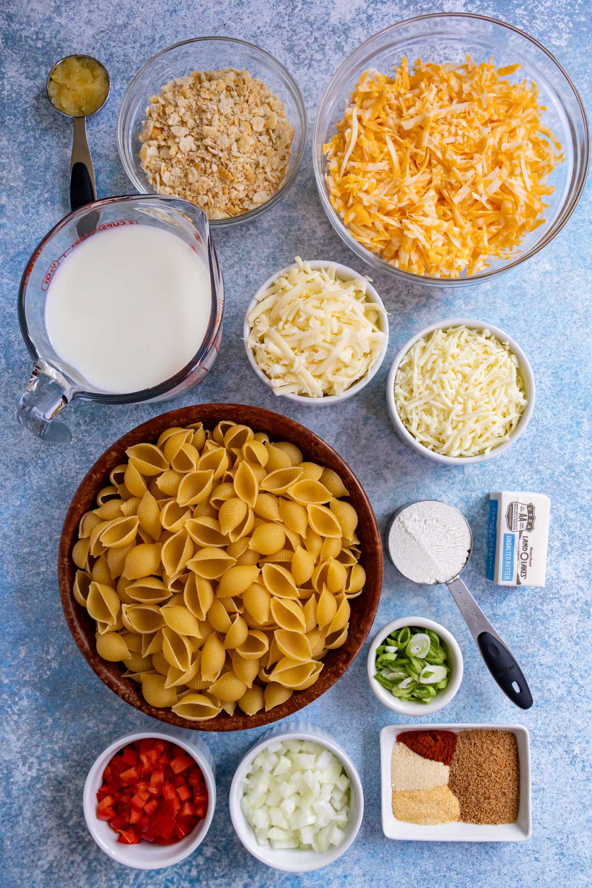 Ingredients for Cajun macaroni and cheese on a blue concrete background.